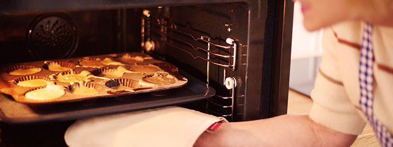 Woman placing muffins in an oven