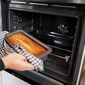 woman removing cake from electric fan oven